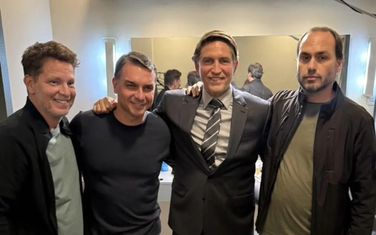 Flávio ao lado de Mario Frias (à esq.), produtor do filme, Jim Caviezel, ator que interpreta Jair Bolsonaro, e Carlos Bolsonaro
								
								-
								
								Crédito: Reprodução